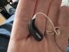 closer shot of black oticon zircon rechargeable hearing aid in palm of hand