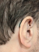 Close up of black lumity aid shown behind ear blending in with black hair of user