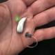 Lumity 70 rechargeable hearing aid in hand with green indicator light on