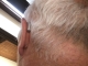 a single oticon real 1 in color silver sitting behind the ear matching users hair color