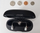 2 real hearing aids in a charger next to coins laid out on a table to show scale
