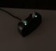 Blurry image of 2 moment sheer 330 hearing aids being charged in a dark room with 2 glowing green indicator lights on the charger