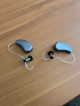 Silver grey mRIC RD moment hearing aids laying side by side on table