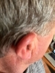 Close up of silver grey hearing aid behind the ear blending well with hair color