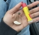 The same hearing aid in users hand next to chapstick for scale