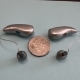 Silver Grey Phonak Audeo Sphere Infinio 90 hearing aids with a quarter