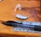 A single right audeo sphere 90 hearing aid laying flat on table with earmold, next to ruler showing small size