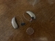 pair of lumity 70 rt hearing aids next to quarter for size comparison