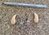 pair of sphere 90 hearing aids in sand beige on counter next to pen for scale