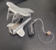 Oticon Zircon 1 in black on table next to staple remover for scale