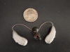 Pair of Phonak Audeo Sphere Infinio 90 in silver gray next to quarter for scale