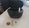 Oticon Intent 1 miniRITE R in silver in charger next to penny for scale