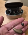 phonak audeo infinio ultra sphere 90 in sand beige in hand next to open charger