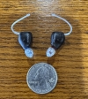 Pair of Oticon zeal next to quarter for scale