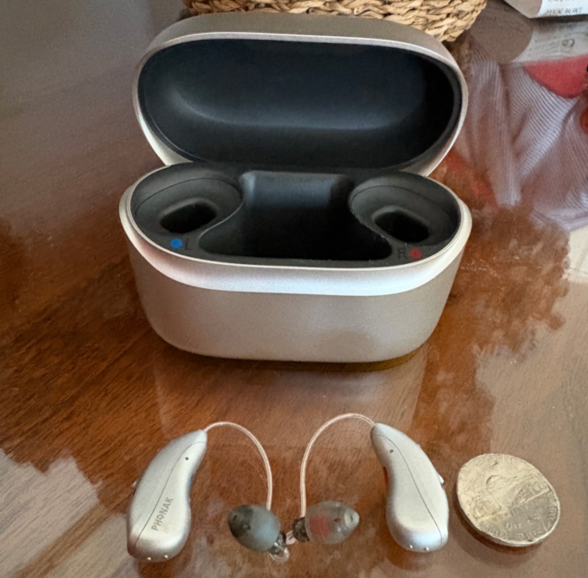 Pair of Infinio ultra 70 hearing aids in silver gray next to charger on table