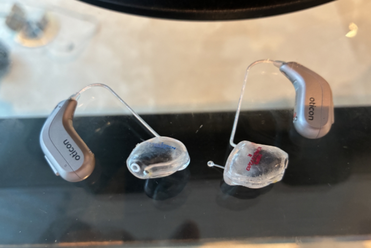 pair of oticon intent 1 with ear molds attached laying flat on table