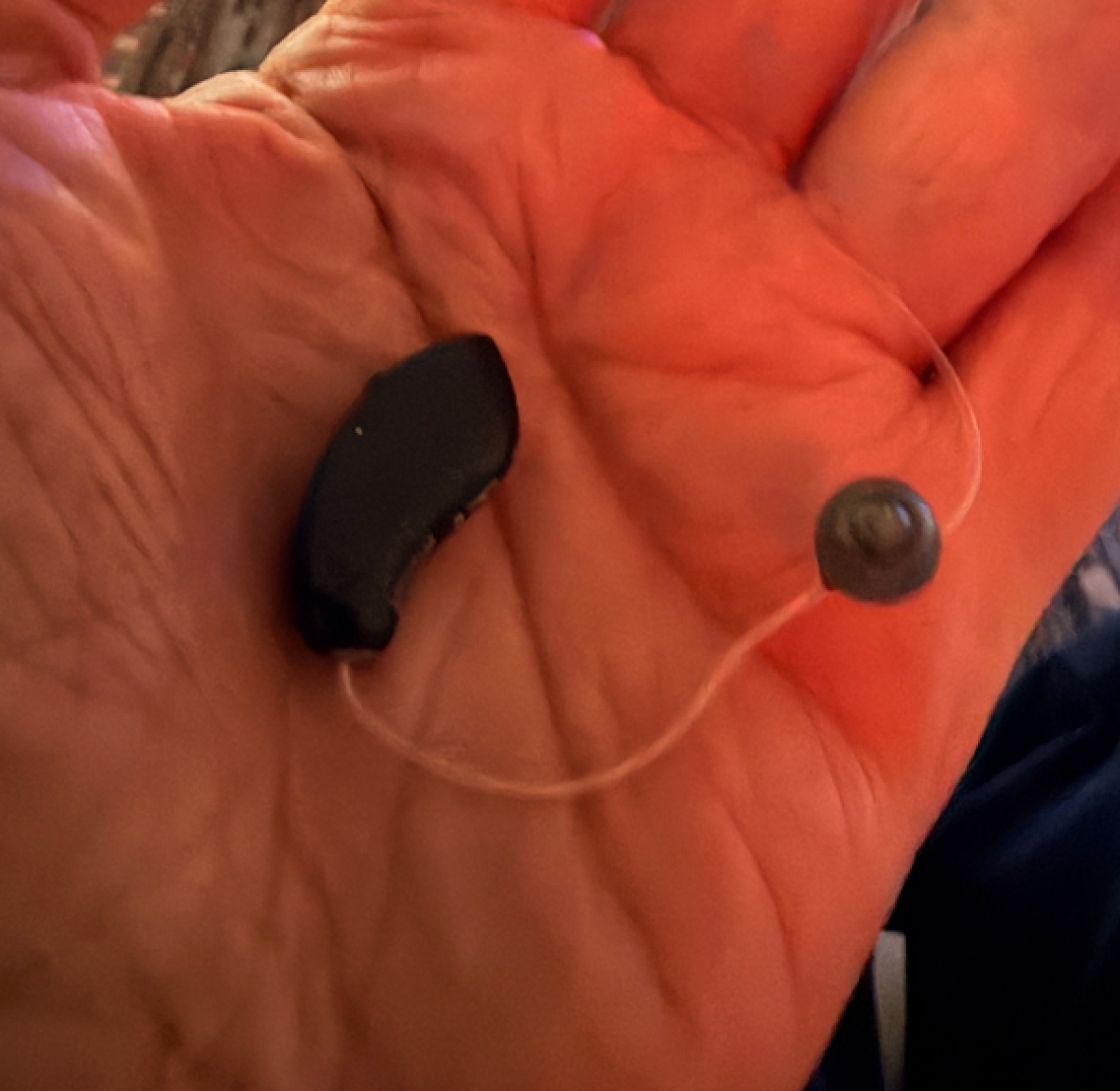 Starkey Omega AI 24 in black in palm of hand