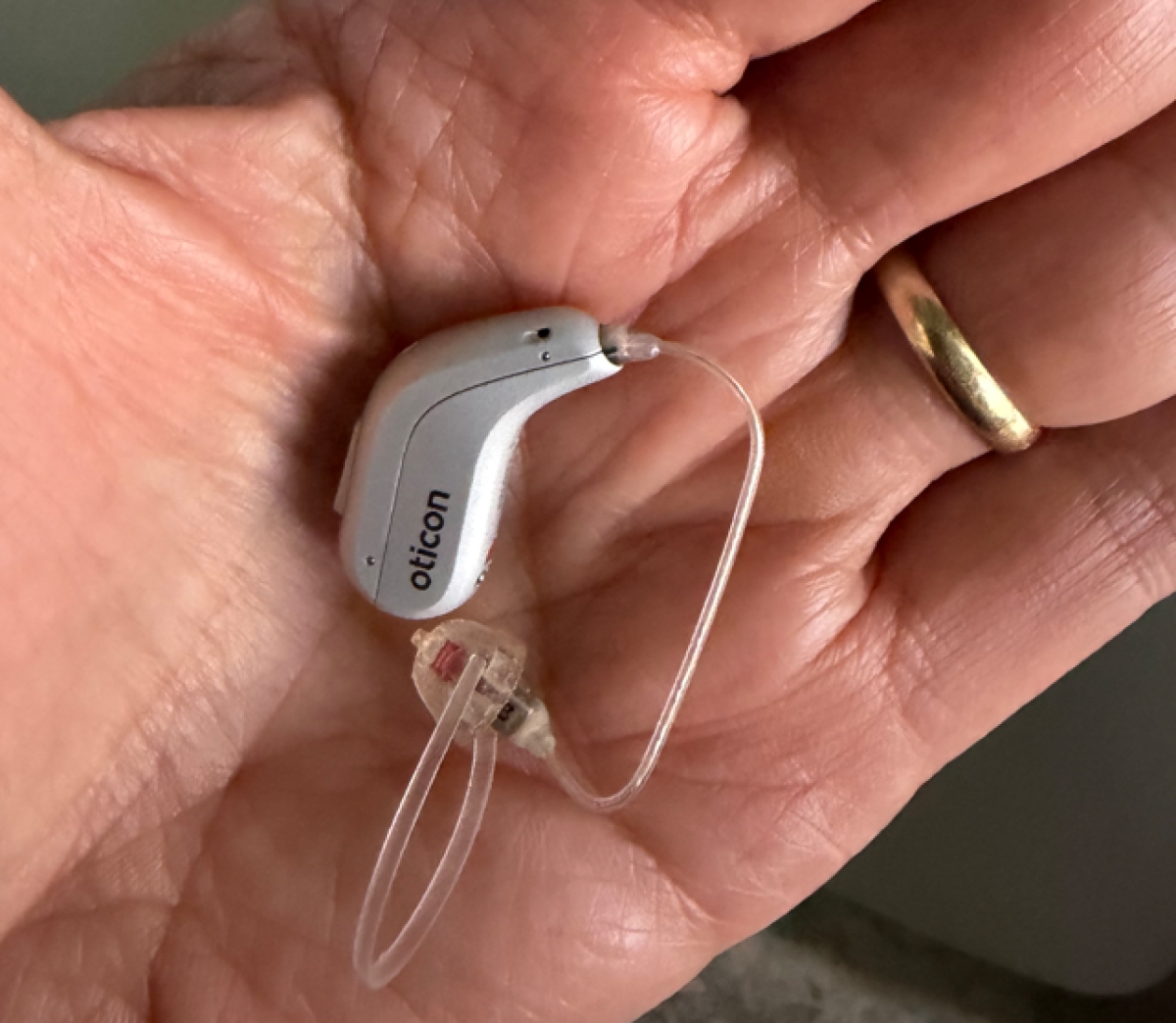 oticon intent 1 in silver in palm of hand