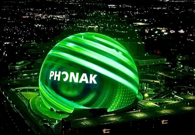 The Las Vegas Sphere venue lit up in Phonak green displays